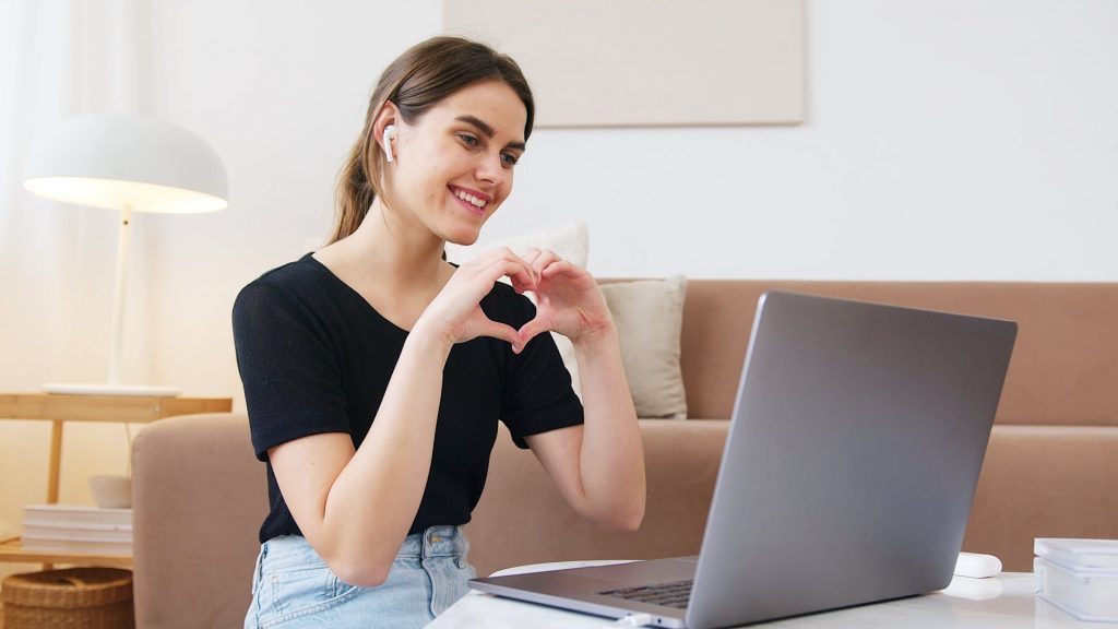 woman making heart with hands while having video call