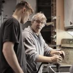 workers handling detail by pneumatic tool in workshop