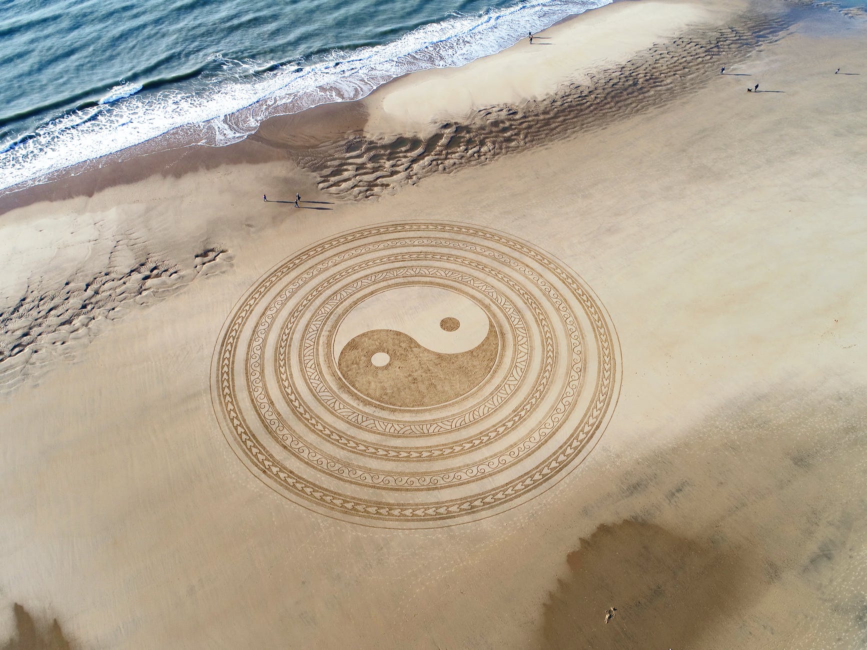 yin yang symbol on brown beach sand trevas e iluminação
