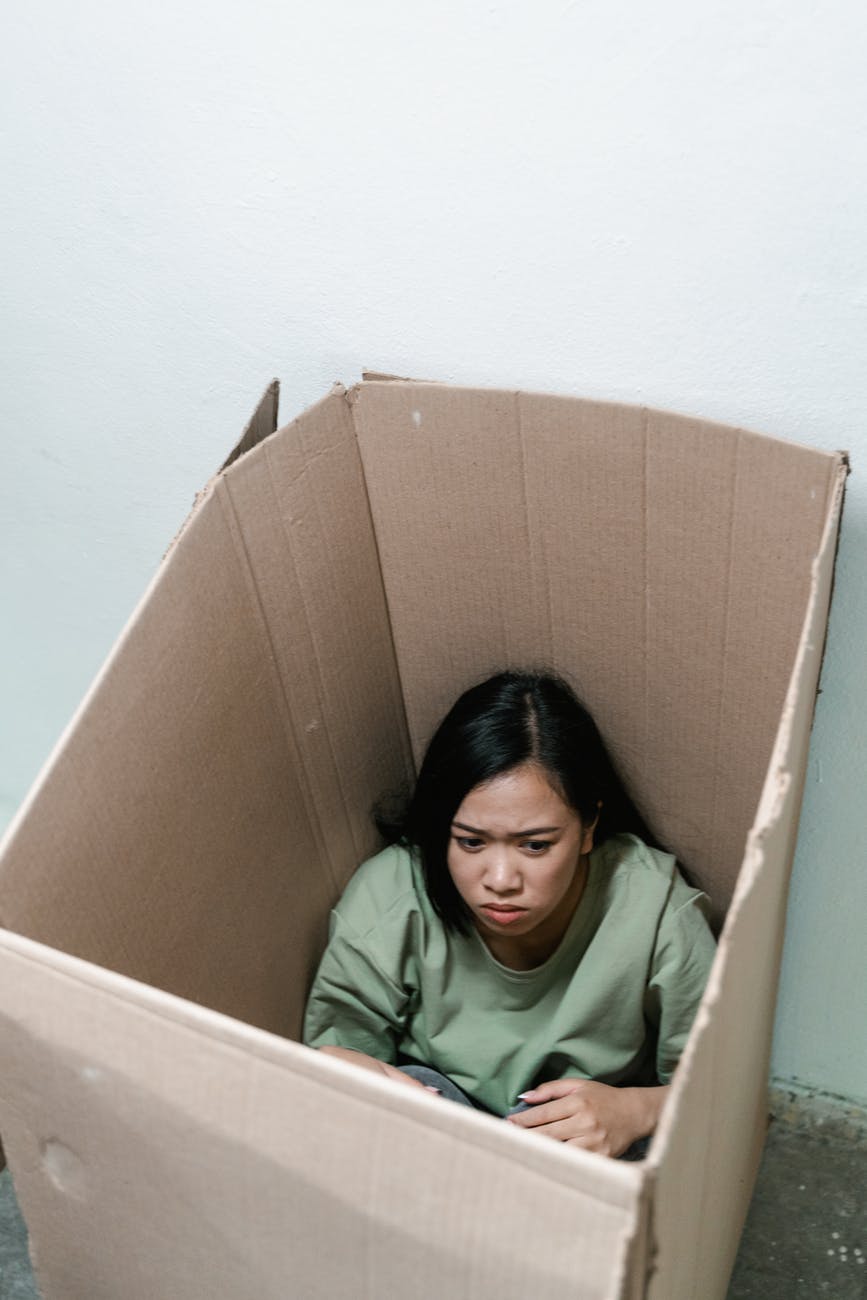 a fearful woman having claustrophobia in a cardboard box ansiedade e adolescência
