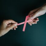 câncer de mama e outubro rosa hands holding breast cancer pink paper ribbon