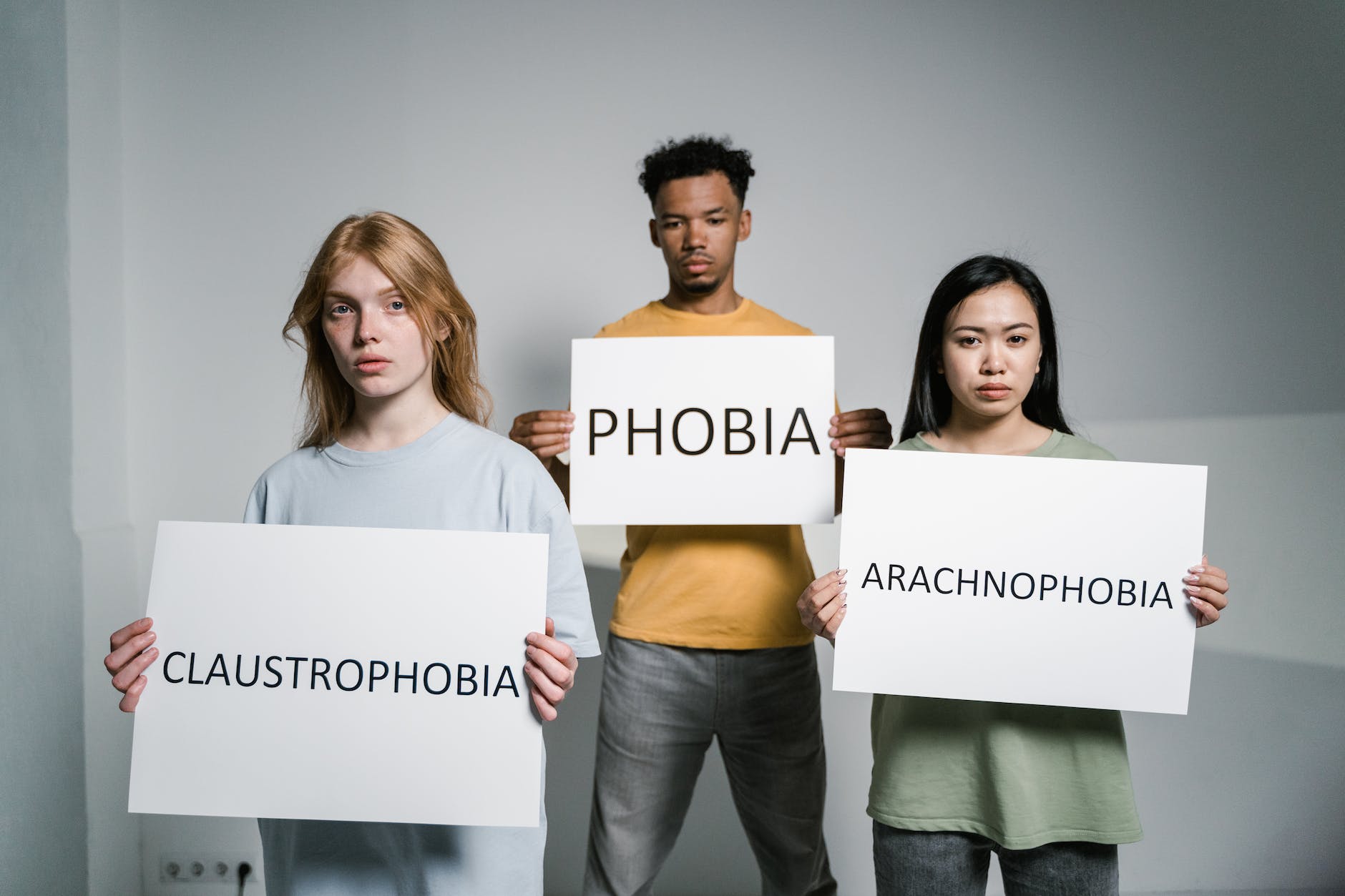 people holding signs of different forms of phobia claustrofobia
