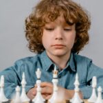 close up photo of a serious boy looking at the white chess pieces