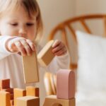 little girl playing with wooden blocks at home